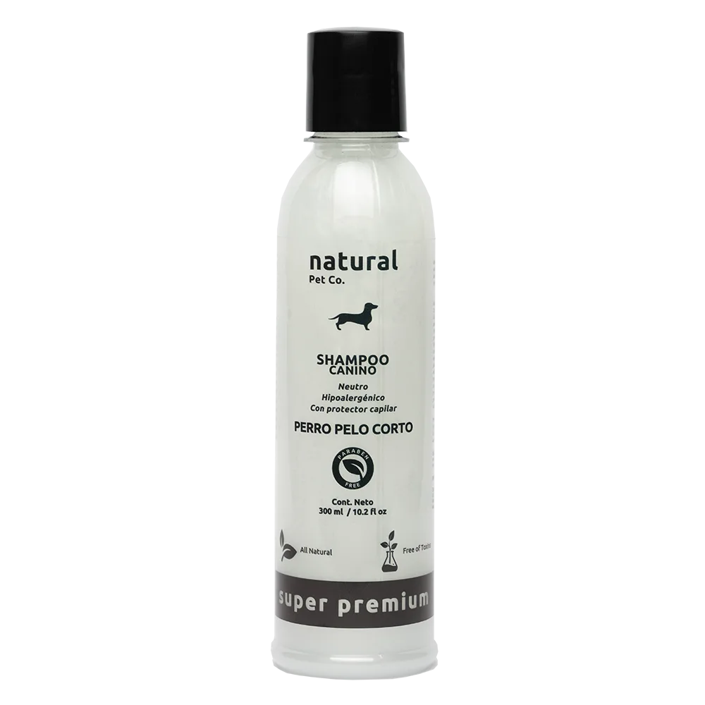 Frasco transparente con shampoo color blanco, es el producto: Shampoo Pelo Corto de la marca boliviana Natural Pet Co. Tiene una tapa color negra, texto color negro y un ícono de negro de un perro en la portada