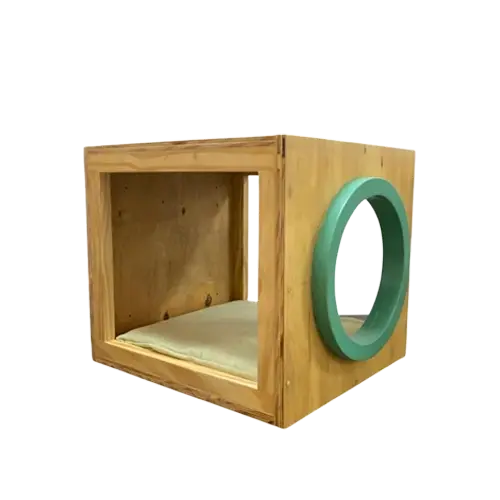 Mueble de madera para gatos. Es una caja con forma de cubo que tiene una abertura circular de color verde en el costado izquierdo.
