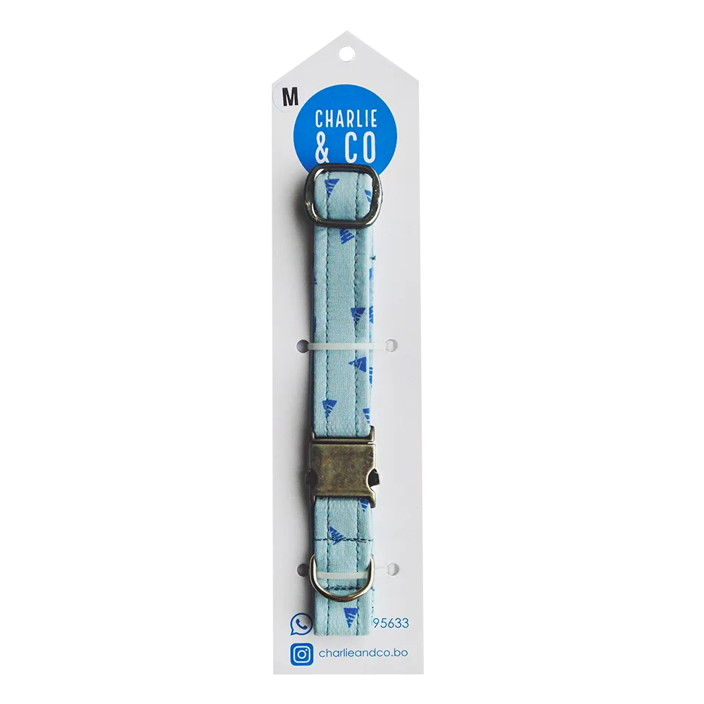 Imagen de Collar Celeste Con Triángulos Charlie & Co. en su empaque original. Es un collar celeste con triángulos azules y hebilla de metal de talla m