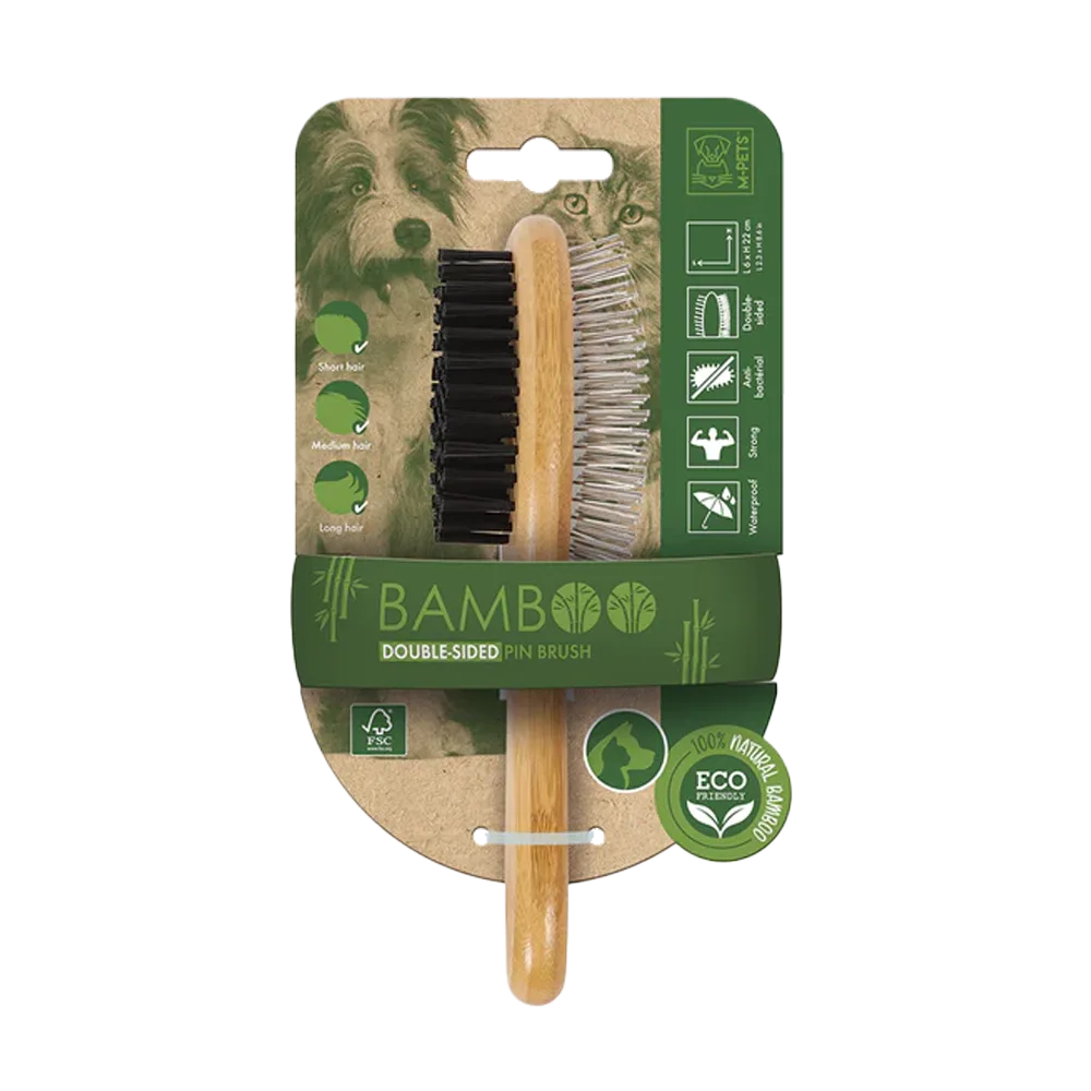 Cepillo Bamboo Doble Cara de M-Pets, es un cepillo ecológico hecho de bamboo ovalado que tiene una cara de cerdas negras suaves y otra de pines metálicos para scar el pelo muerto, en su empaque original que es de cartón con tonos verdes