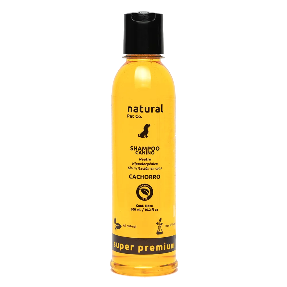 Frasco transparente con shampoo color amarillo, es el producto: Shampoo para Cachorros de la marca boliviana Natural Pet Co. Tiene una tapa color negra, texto color negro y un ícono de negro de un perro en la portada