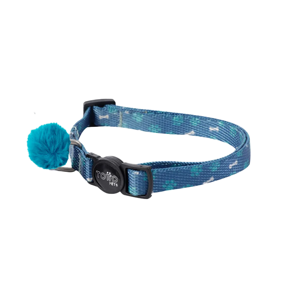 Imagen de collar Meow de la marca Totto, es un collar para gatos color celeste con patitas verdes con una hebilla plástica negra y una argolla de metal donde le cuelga un pompom calipso